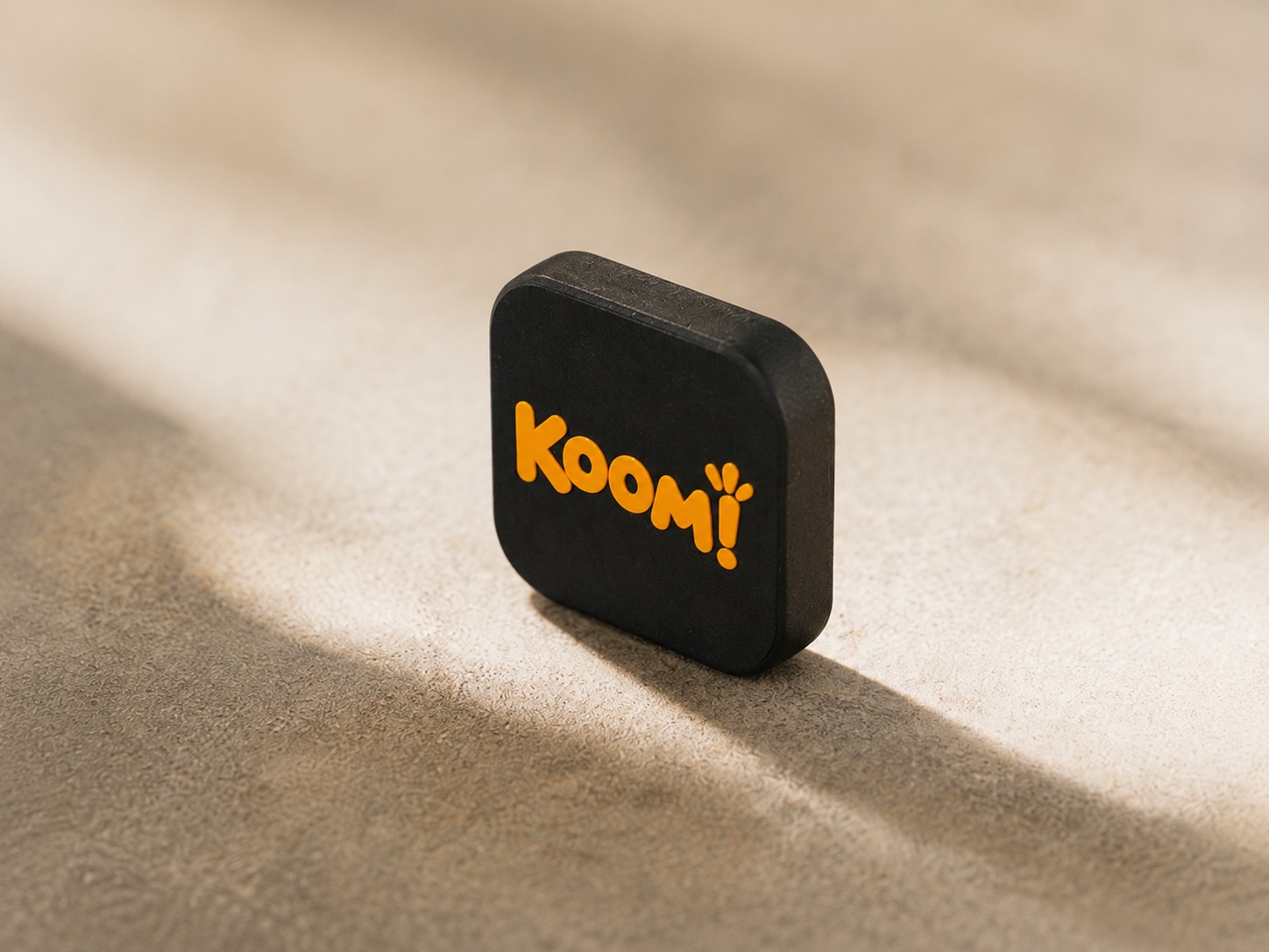 תג Koom! עומד על משטח אבן, מואר באור בוקר רך